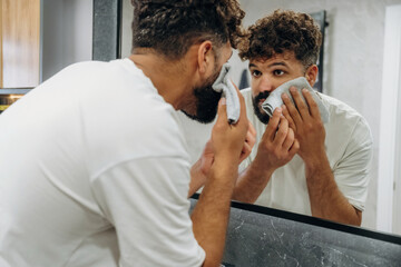 Applying shaving cream. Guy is in the bathroom, taking care of his appearance