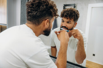 Fototapeta premium Brushing the teeth. Guy is in the bathroom, taking care of his appearance
