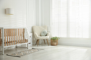 Stylish baby's room with crib and armchair. Interior design