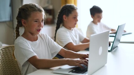 Child types on laptop computer as girl and boy student sit in classroom school area focusing on education and learning with smile and cooperative interaction during digital study and skill development - Powered by Adobe