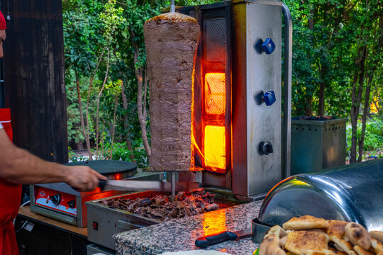 Meat rotisserie at the luxury hotel's buffet. A rotisserie chef is carving traditional Turkish rotisserie meat.Hatay usulu et tavuk doner durum. Lavash doner kebab ( zurna  durum )  or shawarma sliced