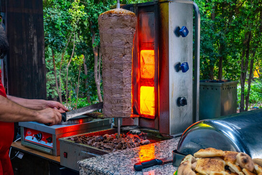 Meat rotisserie at the luxury hotel's buffet. A rotisserie chef is carving traditional Turkish rotisserie meat.Hatay usulu et tavuk doner durum. Lavash doner kebab ( zurna  durum )  or shawarma sliced