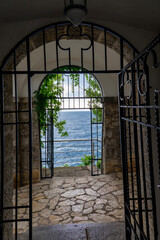 Arched gate with ivy overlooking tranquil blue sea and horizon, scenic coastal view Lungormare Opatija Croatia