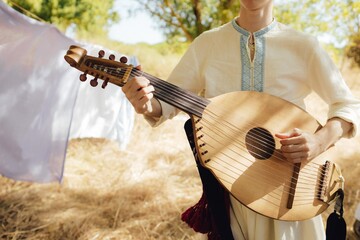 Close-up of man's hands with Ukrainian traditional musical string instrument - kobza. Folk ethnic music, cultural heritage, authentic national clothing. Part of the series.