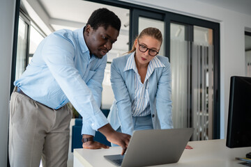 Business colleagues collaborating on laptop project in modern office space