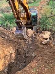 Yellow excavator working on digging a ground trench in winter to build extra ground