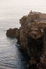 Lighthouse at Nazare’s Cliff-Edge Overlooking Atlantic Ocean, Waves Crashing and Dramatic Coastal Panorama in Portugal