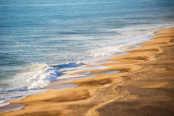 Golden Sandy Beach with Rolling Atlantic Ocean Waves in Nazare, Portugal, Famous Surf Destination