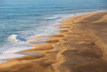 Golden Sandy Beach with Rolling Atlantic Ocean Waves in Nazare, Portugal, Famous Surf Destination