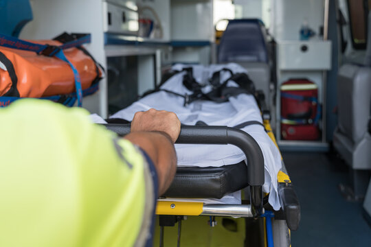 Paramedic is pushing an empty stretcher inside an ambulance ready for emergency intervention