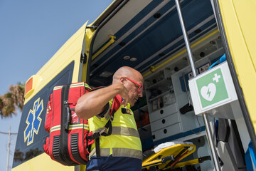 Paramedic adjusting backpack exiting ambulance on a sunny day © Jorge