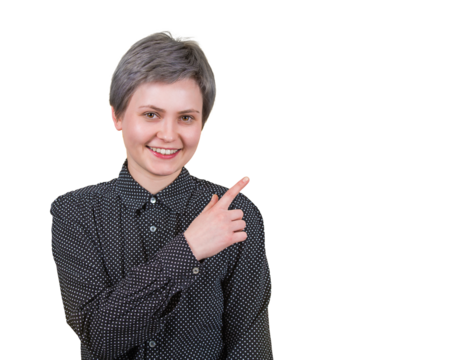 Positive young woman with short hairstyle, pointing forefinger aside, looking joyful to camera, wears dotted black shirt, isolated on transparent background with copy space