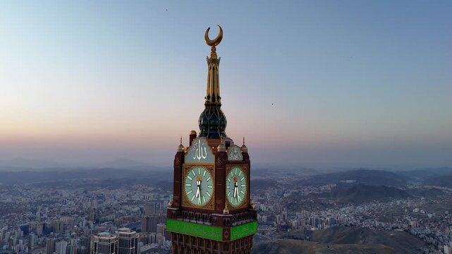 drone footage of Mecca, Saudi Arabia, filmed at sunset. The video captures the vast urban landscape with residential buildings, modern towers, and surrounding mountains bathed in golden hour light