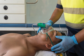 Paramedic putting oxygen mask on patient lying in ambulance