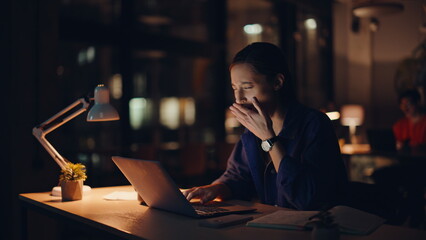 Sleepy employee browsing laptop at night workspace closeup. Tired businesswoman
