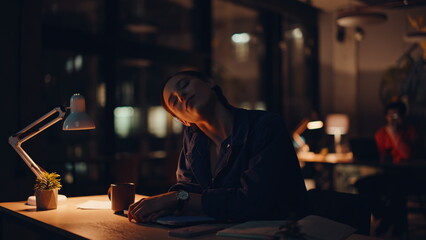 Professional stretching neck night workplace with closed office laptop closeup. 