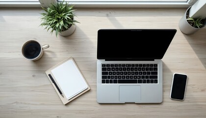 Top-down view of wooden desk with laptop, smartphone, coffee mug, and notebook – modern work from home setup