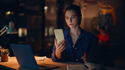 Joyful student browsing mobile phone message at dark workplace light closeup.