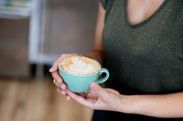 Barista holding a cup of latte with heart-shaped foam art