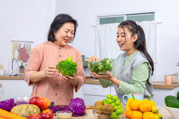 Mother and daughter in kitchen preparing fresh vegetable salad, senior pension woman and young adult daughter mixing ingredient, Asian family lifestyle relationship healthy nutrition bonding wellness