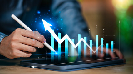 Hand using digital pen on tablet with rising graph and bar chart, representing business analytics, financial performance, digital growth, data visualization, and strategic planning in modern finance.