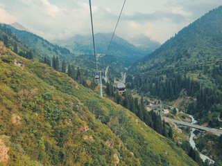 August 11, 2024, Almaty, Kazakhstan. a cable car moving through the green mountains between Medeu and Shymbulak under a clear sky, scenic and peaceful landscape.