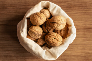 A fabric bag filled with walnuts on a rustic wooden surface, symbolizing natural and sustainable living.