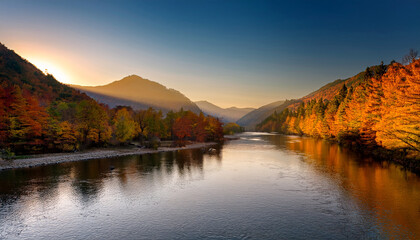 Fototapeta premium Picture Of A Tranquil River Surrounded By Mountains And Autumn Foliage During The Golden Hours Of Fall