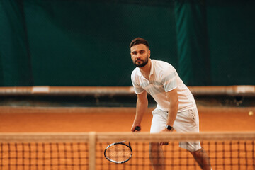 Front view. Man is playing tennis indoors in the hangar