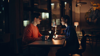 Overtime colleagues communicating office night space. Smiling man woman talking 