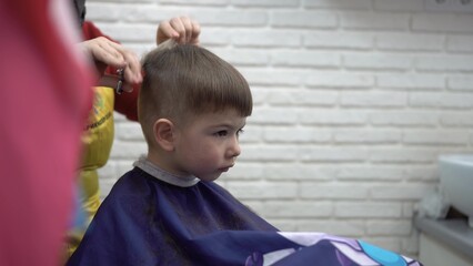 toddler smiling in barber chair while getting a haircut