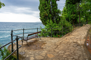 Stone seaside path with a bench Lungomare with railing along Adriatic coast in Opatija, Croatia