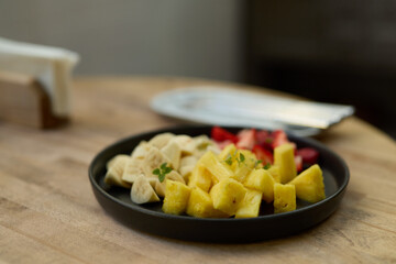 A vibrant assortment of freshly cut fruits beautifully arranged on an elegant black plate