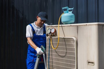 Skilled Technician Servicing Air Conditioning Unit with Tools and Equipment Outdoors in Bright Daylight