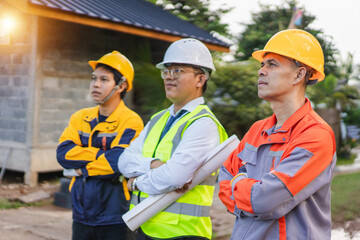 Construction Team on Job Site with Plans and Safety Gear Watching Progress of Project