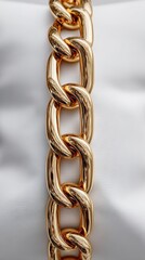 Gold chain with intricate links resting on a soft white surface in an elegant display of fashion and luxury