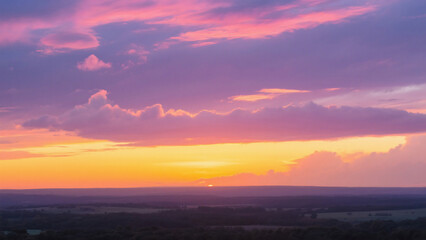 Fototapeta premium A scenic view of a colorful sky with pink and purple clouds at sunset over a dark horizon landscape
