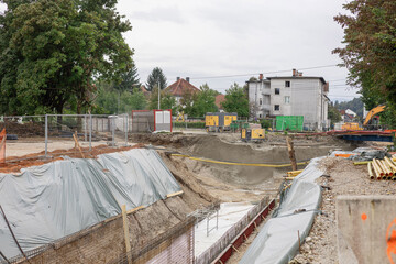 Urban excavation site in i ka, Ljubljana: Deep concrete-lined trench amid sloped earth banks...