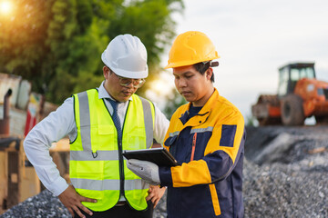 Construction workers reviewing plans on a tablet at a site during sunset, showcasing teamwork and safety in construction industry