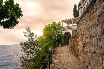 Scenic seaside stone path Lungomare with villa terrace at sunset on Adriatic coast