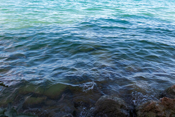 Top down view of calm water surface at Lake Garda turquoise blue water from Sirmione city shoreline