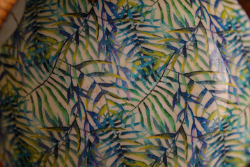 A round wooden bowl with hand-painted leaves on the inside that looks a bit like a jungle