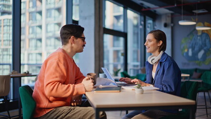 Smiling workers drinking coffee at creative office space. Happy two colleagues
