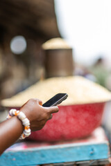 Close Up, Hands of Local African market woman using a smartphone at her outdoor stall. Small business owner, SME.