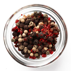 High-quality closeup image of assorted peppercorns in a transparent glass bowl on a white background, viewed from above.