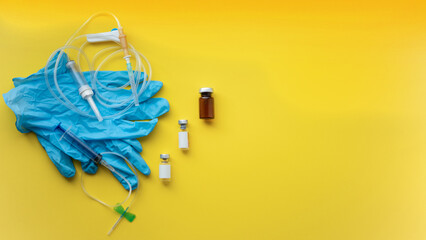 Medical supplies, syringes, catheter, ampoules, gloves, needles on yellow background, flat lay.