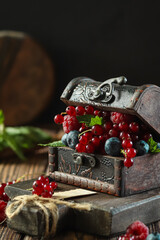 Fresh berries overflowing from an antique treasure chest on a rustic wooden table in a cozy kitchen setting
