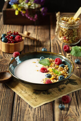 Indulge in a delightful breakfast bowl filled with crunchy granola, fresh berries, and creamy milk, all beautifully presented on a rustic wooden table, creating a cozy and inviting atmosphere