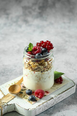 Delicious yogurt parfait layered with fresh berries and granola served in a mason jar on a rustic wooden board