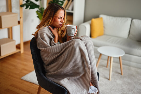 Woman feeling unwell with sore throat at home